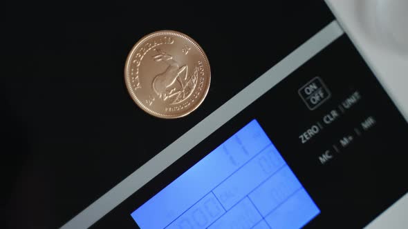 Closeup View of South African Krugerrand Coin is Placed on a Digital Weight Scale alt