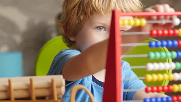 Blond Hair Boy Playing With Wooden Balk And Abacus