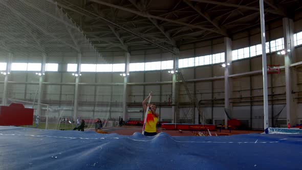 Pole Vaulting - Sportsman in Yellow t Shirt Is Running and Jumping Over the Bar alt
