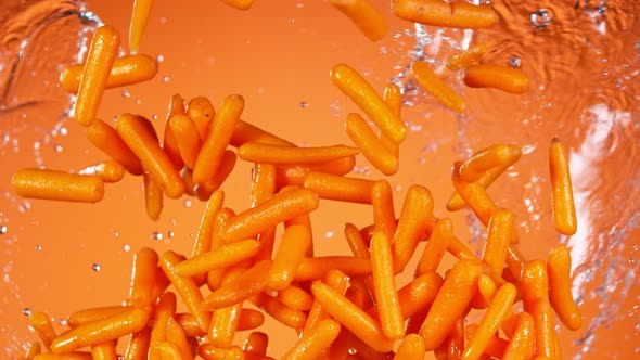 Super Slow Motion Shot of Flying Fresh Baby Carrots and Water Side Splash at 1000 Fps alt