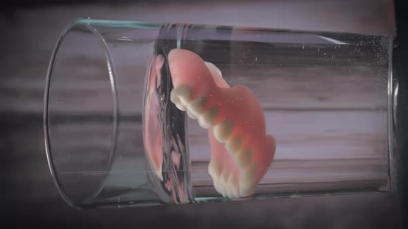 Closeup Shot of Placing Prosthesis Teeth Into a Glass of Water