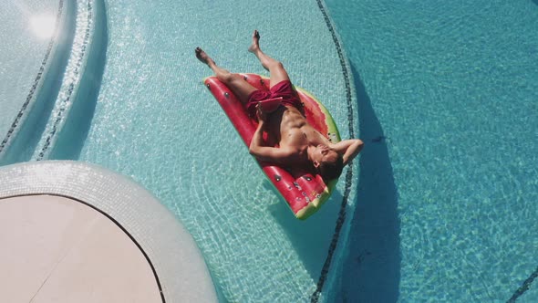 Drone Over Man Relaxing On Inflatable In Pool alt