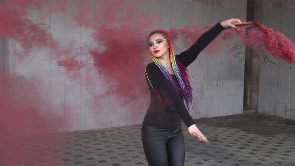 A Girl in a Simple Black Dress with Colored Braids and Rainbow Makeup Posing in Red Thick Smoke in a alt