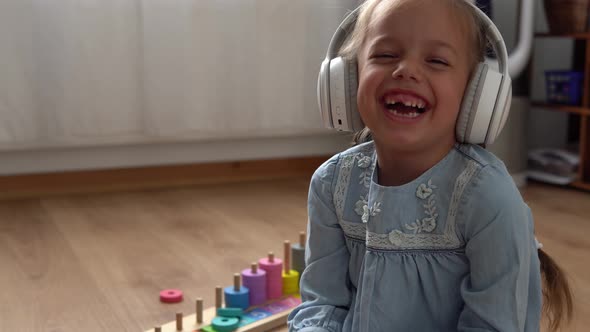 Child Listening Music In Big White Headphones