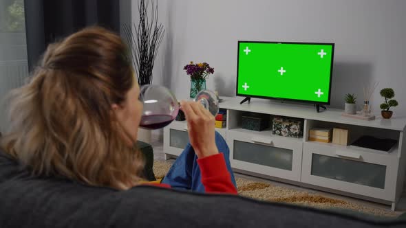 Woman Drink red Wine relaxing on a living room couch while watching tv Greenscreen alt
