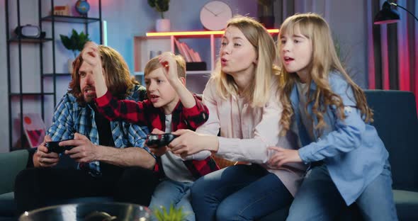 Paretns with Children Having Fun Together while Winning in Videogames at Home alt