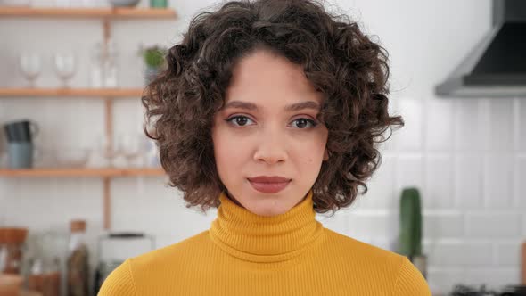Close Up Face Hispanic Curly Woman Looking Camera Standing at Home Kitchen alt