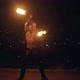 Young Blond Male Spins Two Burning Pois on Black Night City Background. Slow Motion Shot.