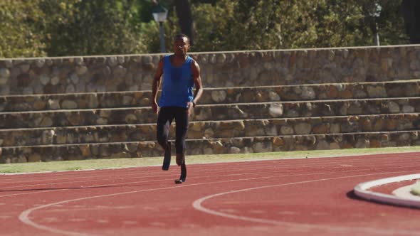 Disabled mixed race man with prosthetic legs running on race track alt