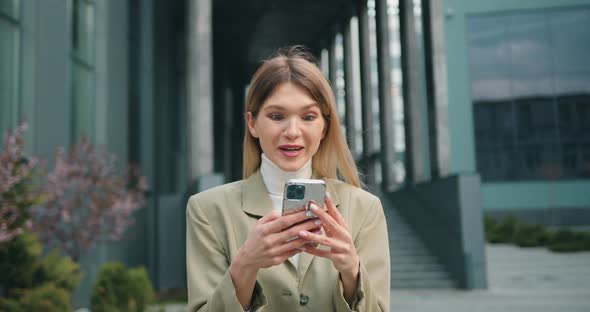 Excited Female User Customer Standing in Street Using Smartphone, Get Amazing Sale Offer Winning alt