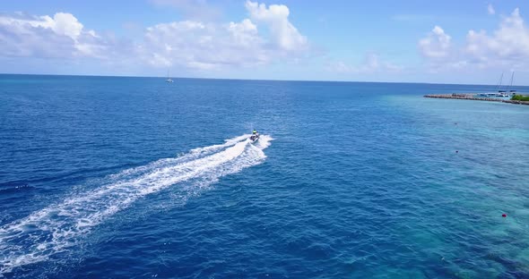 Wide flying clean view of a sunshine white sandy paradise beach and blue sea background in hi res 4K alt