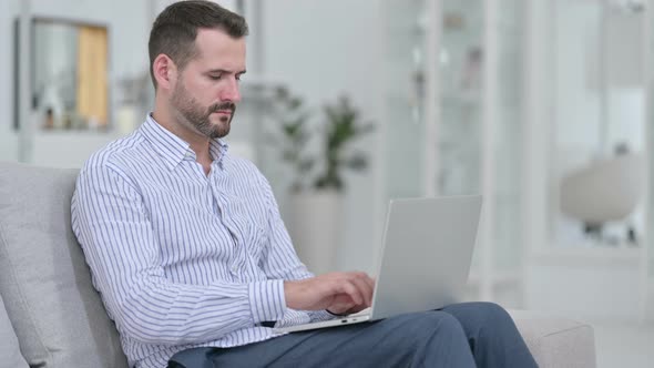 Stressed Young Man with Laptop Having Headache at Home  alt