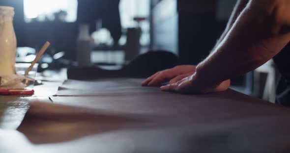 Cropped Artisan Spreading Leather on Table alt