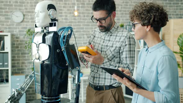 Scientists Checking Robot with Electronic Devices Using Tablet in Office Room alt
