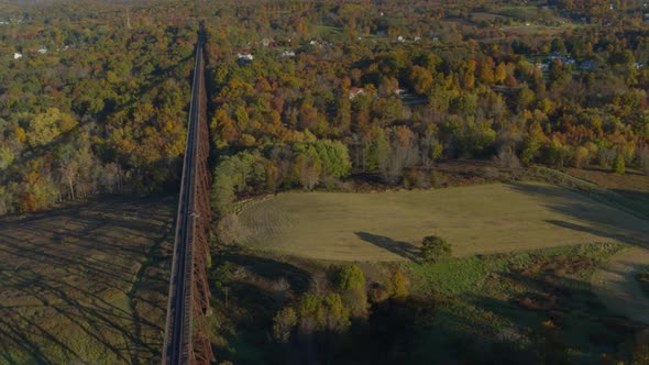 Aerial of railroad bridge over landscape and autumn forest alt