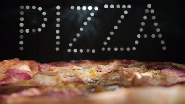 Delicious Fresh Italian Pizza On A Black Background With The Effect Of Light Inscription Pizza