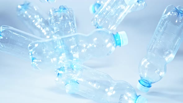 Super Slow Motion Shot of Falling Empty Plastic Bottles on Blue Gradient Background at 1000Fps alt