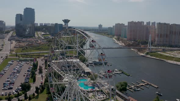 a Ferris Wheel on the River Bank with a Swimming Pool and a Beautiful Summer Landscape alt