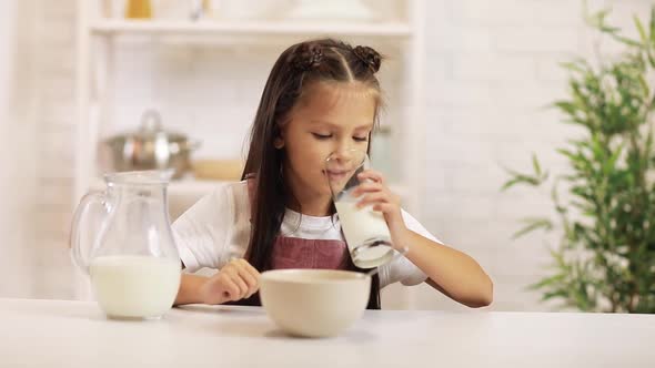 Little Child Girl Drinking Milk in the Kitchen