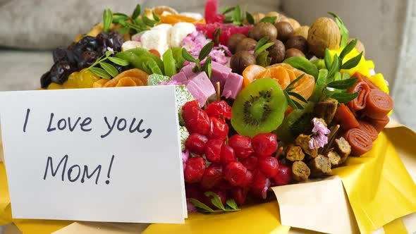 man's hand puts a letter with the inscription I love you mom for a gift of a sweet bouquet of dried  alt