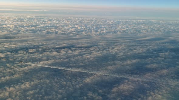 Incredible view from the cockpit of an airplane flying high above the clouds leaving a long white co alt