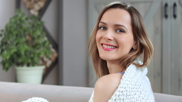 Face of Smiling Domestic Woman Wrapped in Plaid Sitting on Couch alt