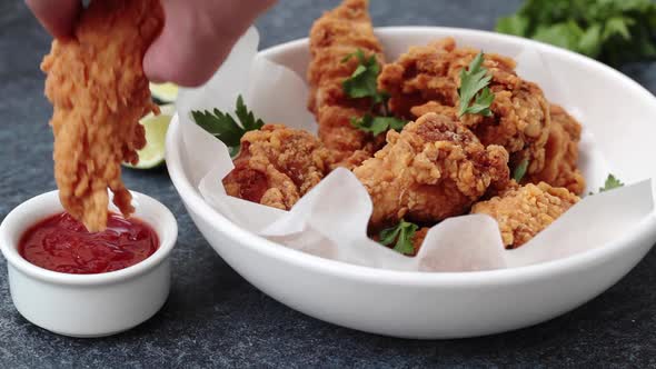 Man Eating Crispy Fried Chicken in a White Bowl with Tomato Sauce. alt