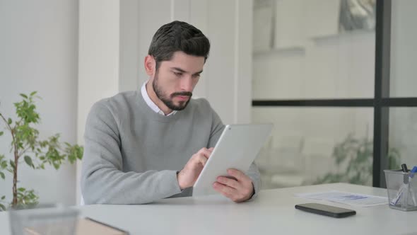 Young Man Using Tablet While Sitting in Office alt