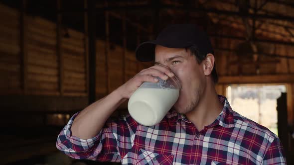 A Farmer Stands on His Farm and Drinks Milk alt
