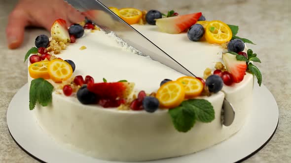 The chef cuts a cake decorated with fresh fruit. Slicing a pie close-up