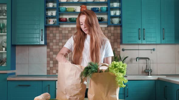 housewife home with paper bag of food and unpacking groceries in kitchen. alt