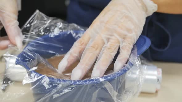 Pastry Chef Covers Melted Chocolate in a Bowl with Cling Film in Contact alt