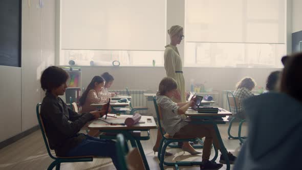 Schoolteacher Walking in Classroom with Students alt