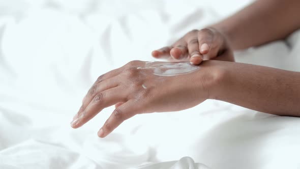 Hands Close Up Black African American Girl Applying Moisturizing Cream and Massage Arm for Softness alt