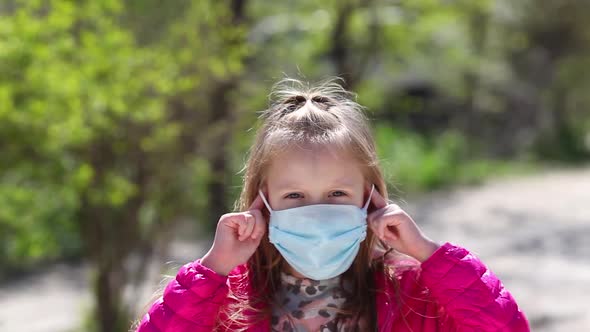 Little girl with medical face mask standing outdoor.