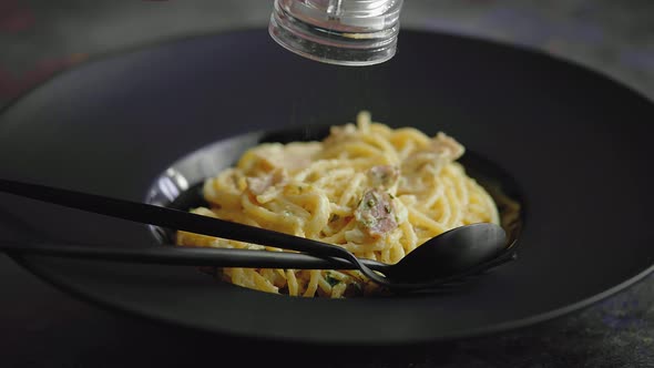 Slow Motion Video of Plate with Spaghetti Carbonara Being Sprinkled with Fresh Pepper alt