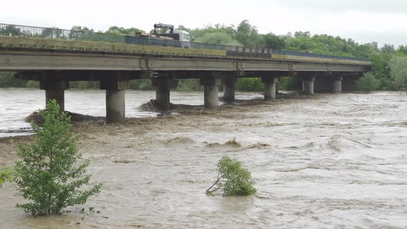 Bridge Over the Overflowing River. Stormy Water Flows. Extremely High Water Level in the River
