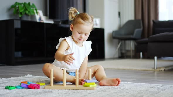 Cute Caucasian Little Girl Playing on the Floor at Home with Eco Wooden Toys alt