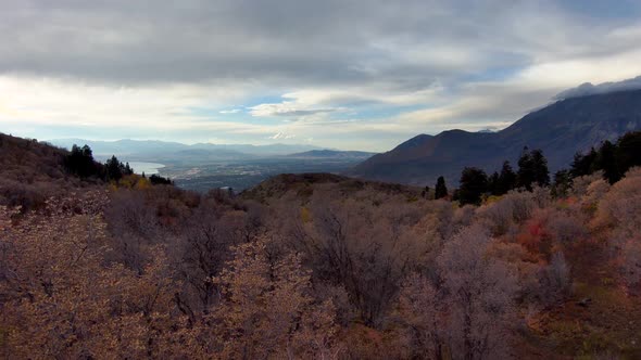 Looking at the distant town from high in the mountains during autumn - aerial pull back view alt
