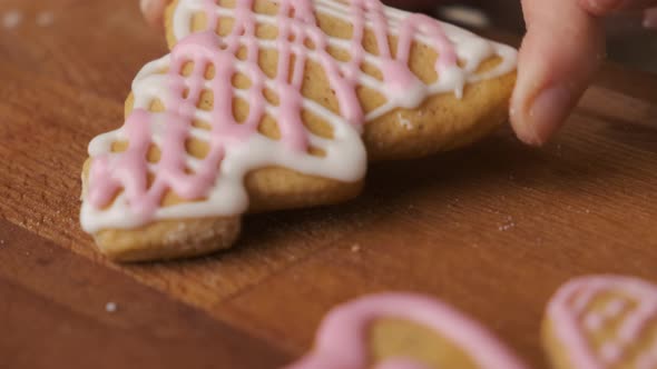 Close Up Woman Hand Puts Christmas Gingerbread in the Form of Christmas Tree on the Wooden Desk alt