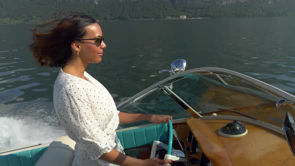 A woman on a classic luxury wooden runabout boat on an Italian lake alt