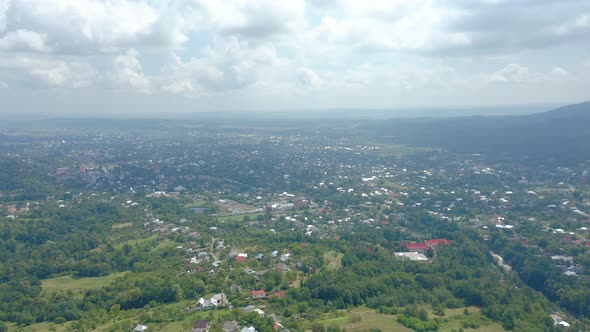 Aerial Drone View of a Big Village in a Mountain Valley Against a Cloudy Sky alt