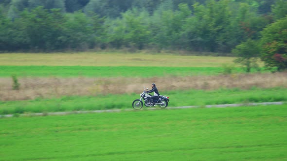Man riding motorcycle on rural road alt
