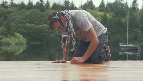 Sanding boat wheelhouse roof planks with sandpaper wearing mask. CLOSE UP alt