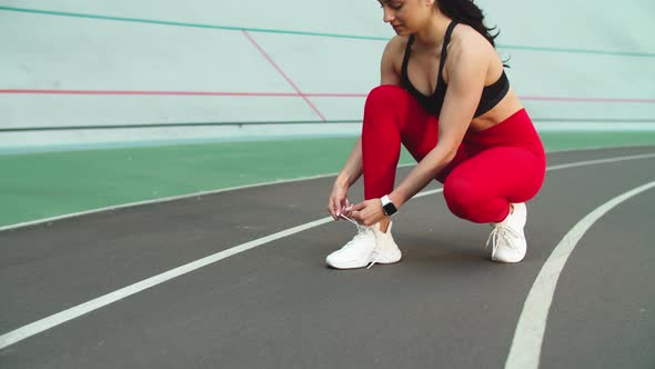 Sport Woman Lacing Up Sneakers for Workout on Track. Woman Runner Tying Up Shoes alt