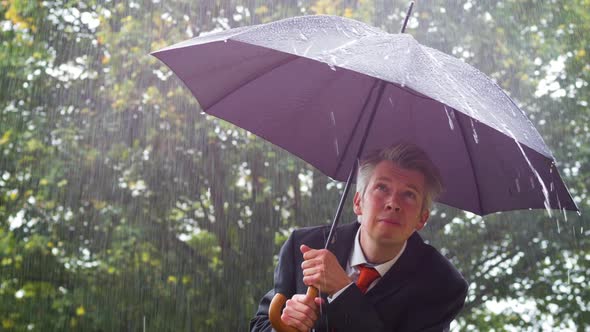 Businessman Sheltering Underneath an Umbrella in the Rain