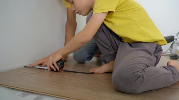 Father and His Little Son Install Laminate on the Floor in Their Apartment alt