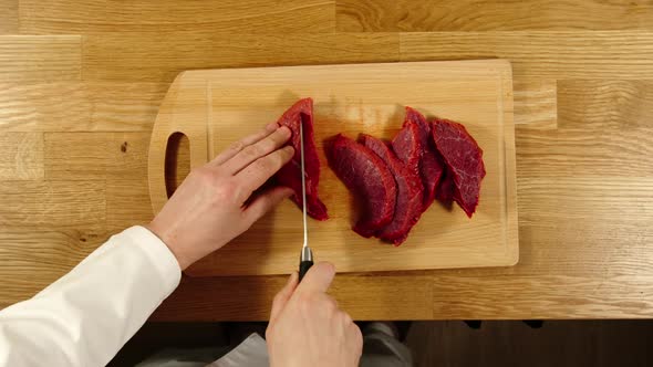 Cook Takes Knife And Cuts Beef Into Slices And Then Into Pieces