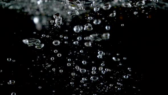 Closeup of fresh kiwis slices falling into clear water with big splash on black background.  alt