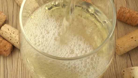 Wine is poured into a glass on the background of wine corks. alt